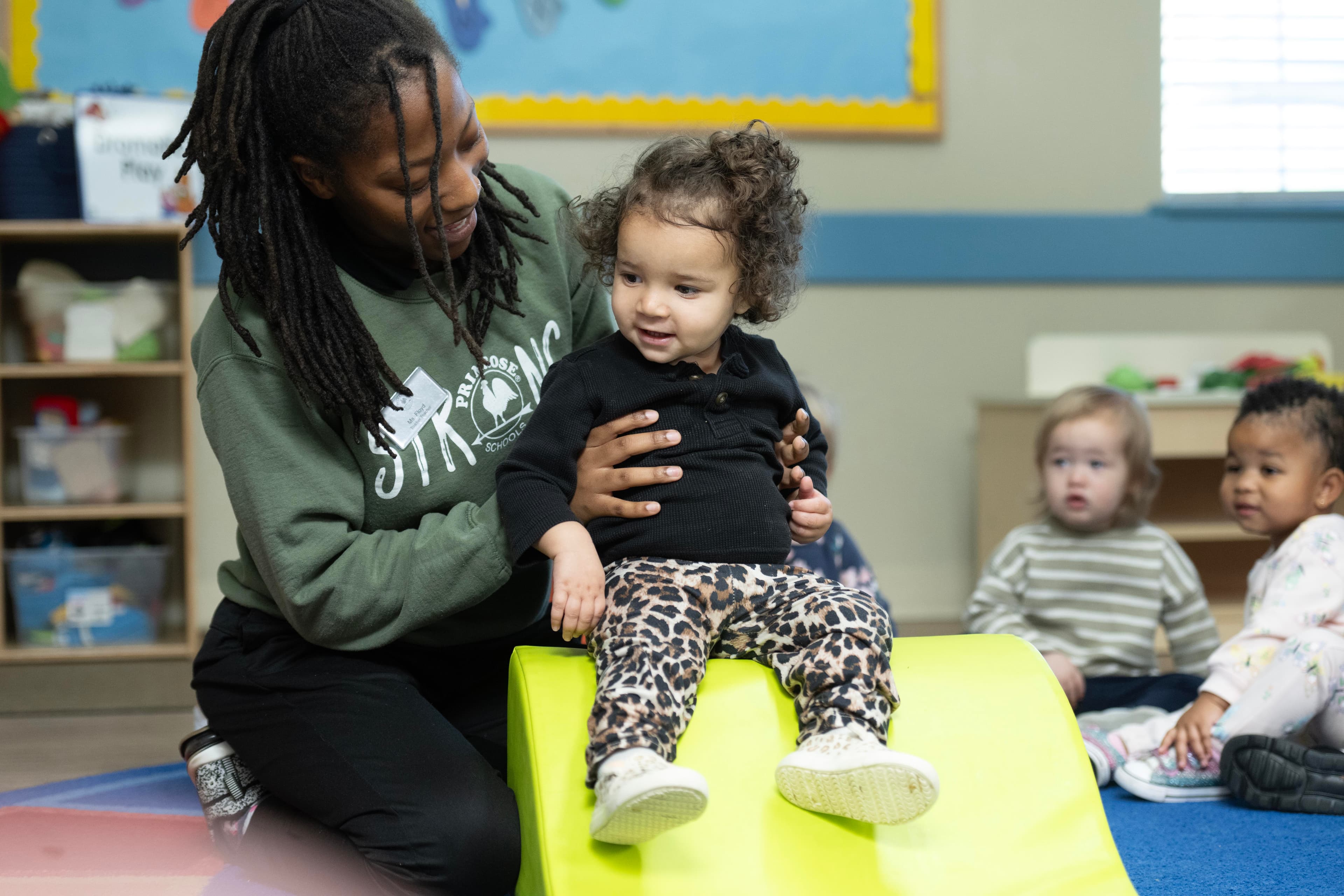 toddler child being guided down a ramp by teacher